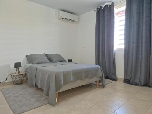 a white bedroom with a bed and a window at Bella - Destination Guyane in Rémire-Camp