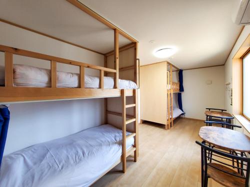a bunk bed room with two bunk beds and a table at ゲストハウスはまなす亭 in Jōnai