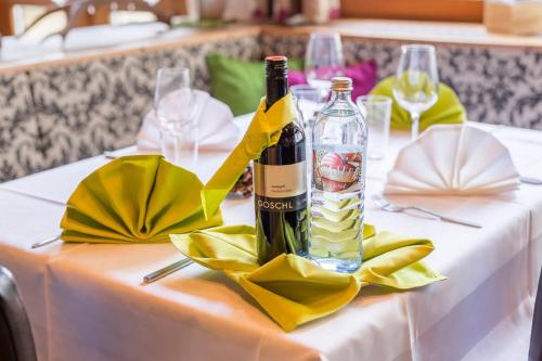 a bottle of wine on a table with yellow napkins at Sterzinger Posthotel in Nassereith