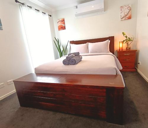 a bedroom with a large bed with a wooden dresser at Deluxe Queen Room - Shared Bathroom in Holmview