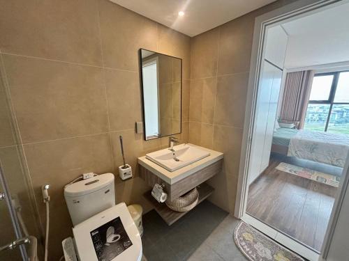 a bathroom with a sink and a toilet and a mirror at 2BR Minato Apartment, Free Swimming Pool & Gym in Hai Phong