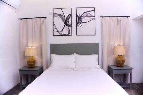 a bedroom with a white bed and two lamps at Purevibe Villa Portland Jamaica - Ocean view suite in Port Antonio