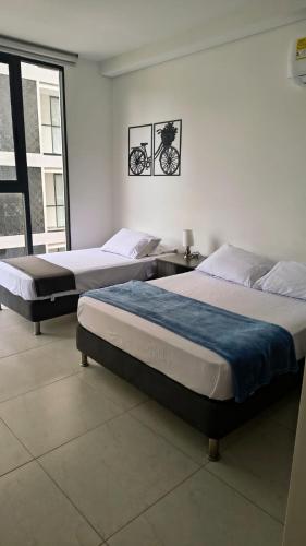 two beds in a white room with at Salinas del Mar Torre 4 Apt 903 - Moderno, equipado y a un suspiro del mar in Santa Marta