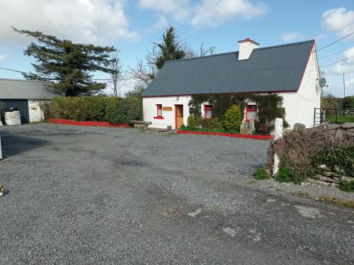 a white building with a black roof and a driveway at Historic old Cottage Co Mayo in Ballinrobe