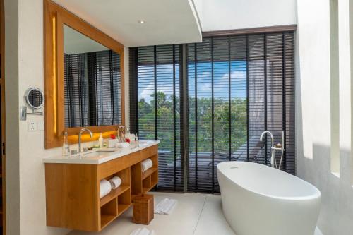a bathroom with a tub and a sink and a mirror at Bumi Kinar Skylight in Ubud