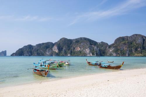 a group of boats in the water on a beach at Ibiza House Phi Phi in Phi Phi Don