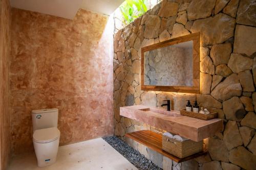 a stone bathroom with a sink and a toilet at Sereno Lombok Resort in Selong Belanak