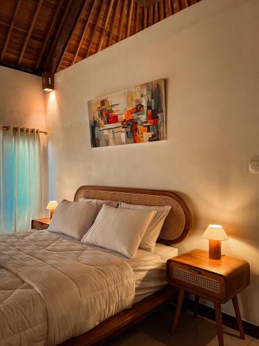 a bedroom with a bed with a table and a painting at The SUN House in Balian