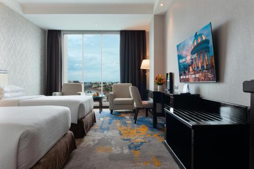 a hotel room with two beds and a desk at Four Points by Sheraton Medan in Medan