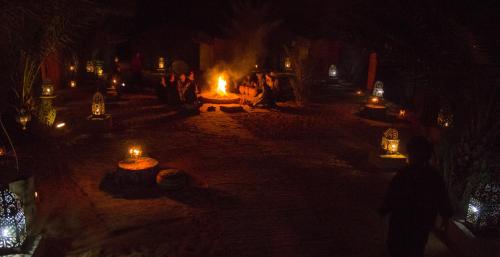 a group of people standing around a fire at night at Auberge Sahara Garden in Lac Yasmins