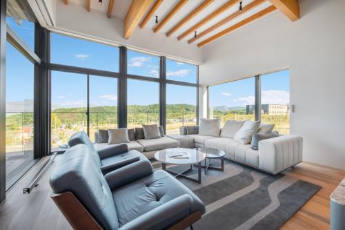 a living room with couches and a table and windows at Shiyuki in Furano