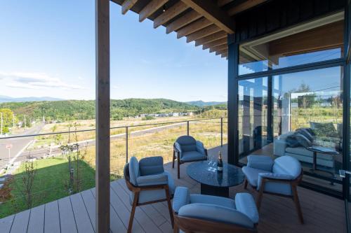 a room with a balcony with a table and chairs at Shiyuki in Furano