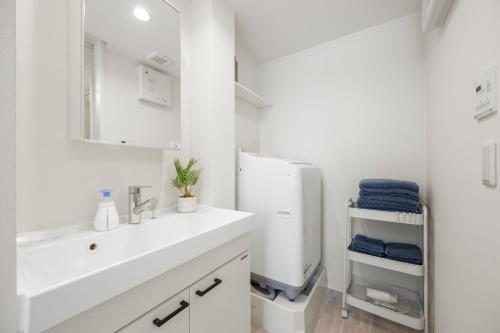a white bathroom with a sink and a refrigerator at 逗子海岸テラス 2階 in Zushi