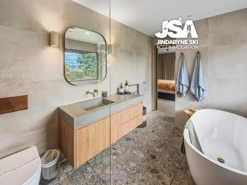 a bathroom with a tub and a sink and a mirror at The Orchard in Moonbah