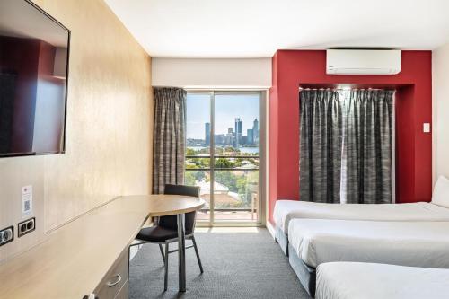 a hotel room with two beds and a table at Metro Hotel Perth in Perth