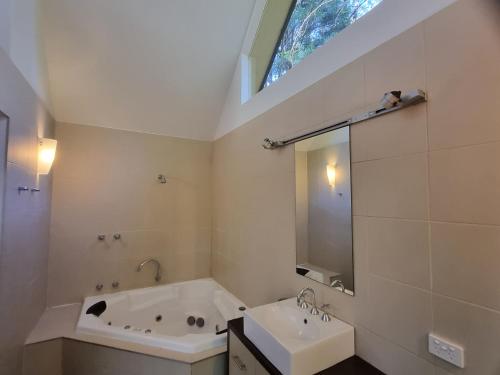 a bathroom with a tub and a sink and a window at Lochiel Cottages - Dandenong Ranges Escape in Olinda