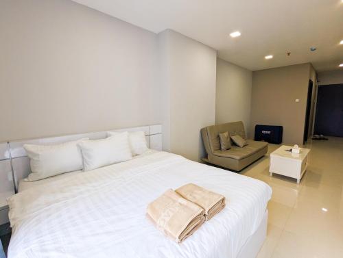 a bedroom with a large white bed and a chair at Lovina Spacious Double Studio at Formosa Nagoya in Jodoh