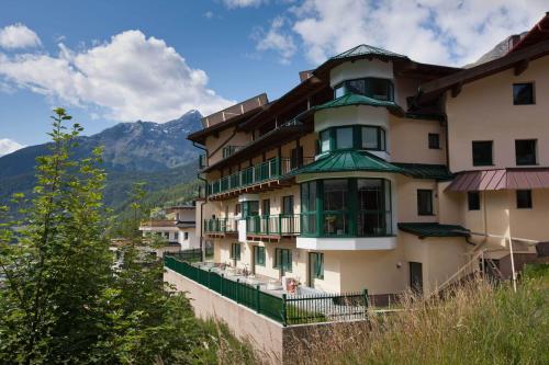 a building on a hill with mountains in the background at Alp Resort Tiroler Adler in Sölden