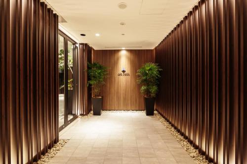a hallway with wooden walls and potted plants at HOTEL MYSTAYS Fuji Onsen Resort in Fujiyoshida