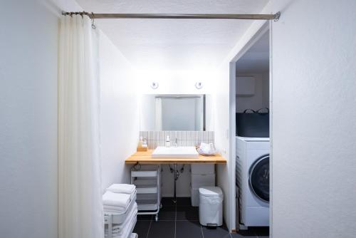a bathroom with a sink and a washer and dryer at いなぎの木箱 in Zentsuji