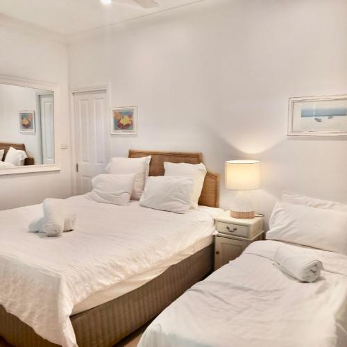 two beds in a room with white walls at Cosy Studio in Port Douglas
