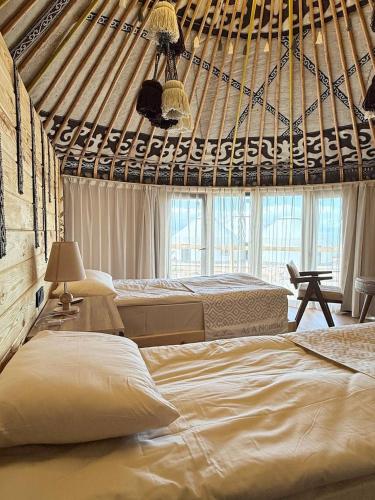 a bedroom with two beds and a large window at Ak-Sai Travel Oimo-Tash Yurt Camp in Kaji-Say