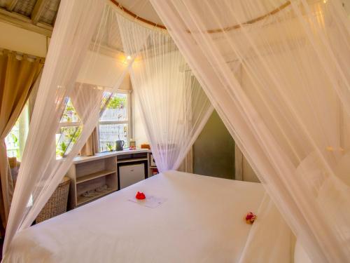a bedroom with a white bed with red roses on it at Ora Resort Gili Meno in Gili Meno