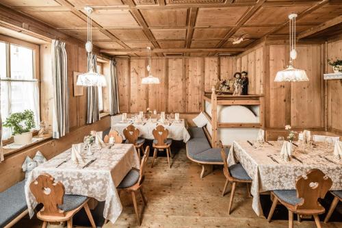 a restaurant with tables and chairs in a room with wooden walls at Hotel Rosental in Luson