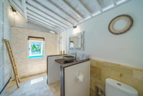 a bathroom with a toilet and a mirror on the wall at Ora Resort Gili Meno in Gili Meno