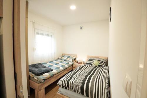 two beds in a small room with a window at Hill House Vrcelinija in Vuglovec
