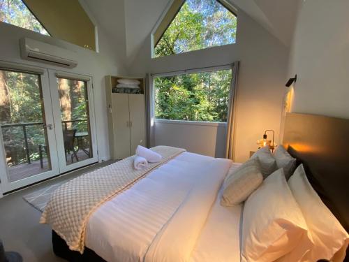 a bedroom with a large bed with two windows at Lochiel Cottages - Dandenong Ranges Escape in Olinda