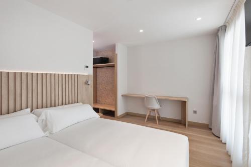 a bedroom with two white beds and a desk at Hotel Arrosadía Iriguibel in Pamplona