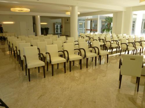 a room with rows of white chairs and tables at Hotel Terme Marine Leopoldo II TERME & SPA in Marina di Grosseto