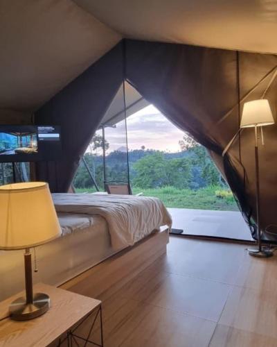 a bedroom with a bed and a large window at Tikumbar Glamping Pelaga in Plaga
