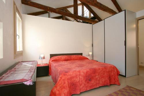 een slaapkamer met een groot bed met een rode sprei bij Casa Alba in Venetië