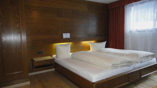 a bedroom with a bed with a wooden wall at Pension Elisabeth in Vent