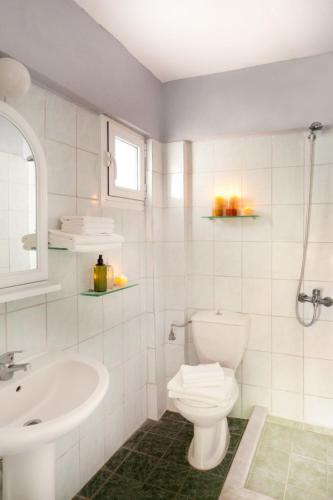 a white bathroom with a toilet and a sink at Haroula Apartments in Sidari