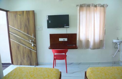 a room with a red chair and a tv on the wall at Prime PG - Coliving Hostel in Hyderabad