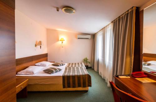 a hotel room with a bed and a window at Plaza Hotel in Varna City