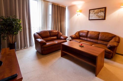 a living room with a leather couch and a coffee table at Plaza Hotel in Varna City