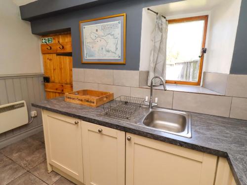 a kitchen counter with a sink and a window at Gamekeepers Cottage in Chillingham