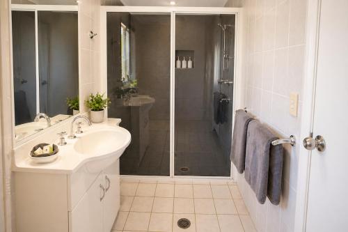 a white bathroom with a sink and a shower at Southern Cross Motor Inn in Narrabri