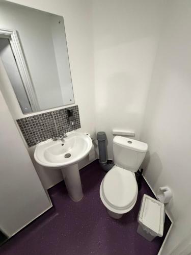 a bathroom with a white toilet and a sink at TBH Hotel in Barking