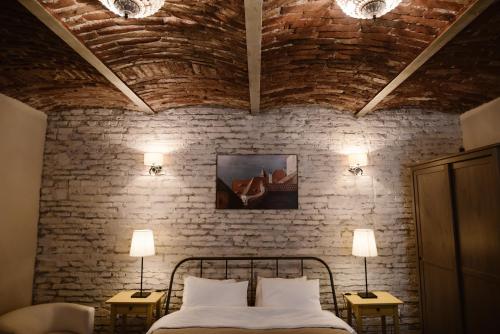 シビウにあるArhiva Loftのレンガの壁のベッドルーム1室、ベッド1台(ランプ2つ付)
