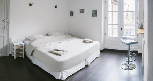 a white bedroom with a bed and a window at A2 PAS in Lectoure