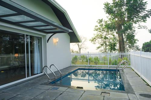 a swimming pool with two chairs next to a house at Parisons Plantation Experiences by Abad in Mananthavady