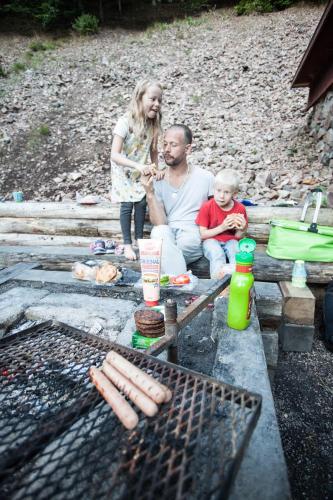 a man and a child cooking hot dogs on a grill at STF Villa Söderåsen B&B in Röstånga