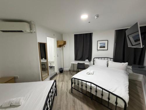 a bedroom with two beds and a mirror at TBH Hotel in Barking