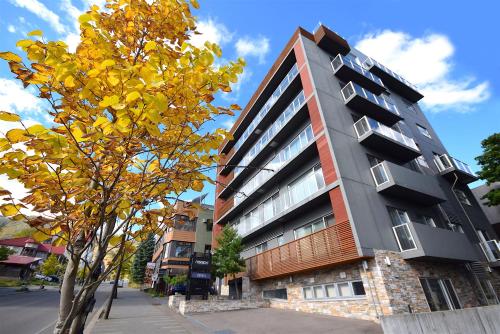 a building on the side of a street next to a tree at The Setsumon in Kutchan