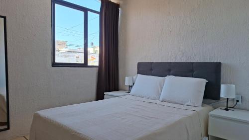 ein Schlafzimmer mit einem weißen Bett und einem Fenster in der Unterkunft Casa Torremolinos en Coto Privado in Zapopan